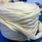 Off-white wool top roving wound as a full bump